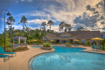 Resort-style swimming pool with lounge chairs looking towards the clubhouse at Lullwater at Blair Stone